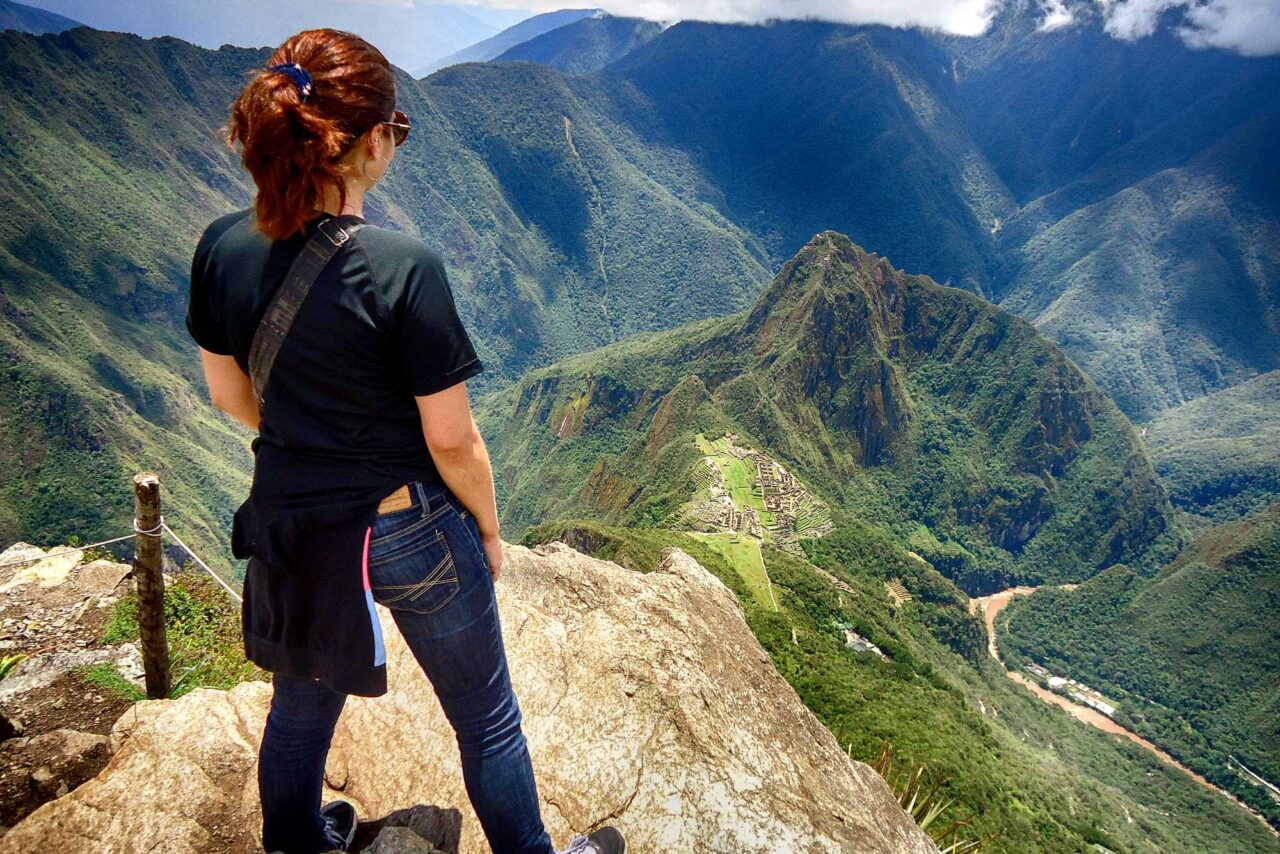 Voyageuse au sommet de la Montaña Machu Picchu, vue sur la citadelle et la vallée de l'Urubamba